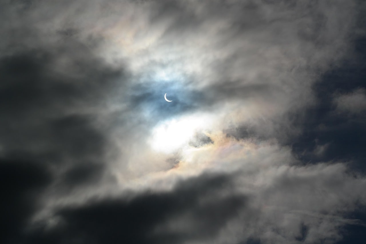 A real partial solar eclipse visible through gaps in a cloudy sky