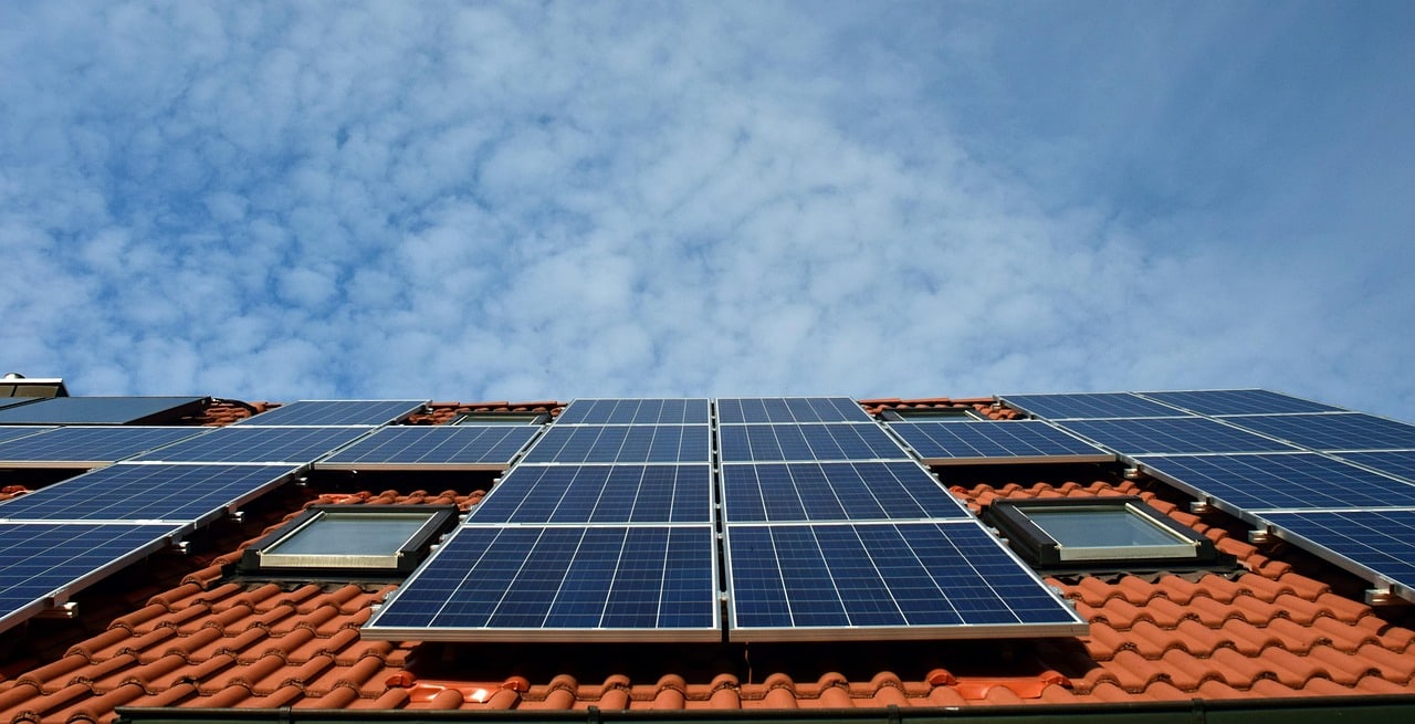 Solar panels installed across a pitched tiled roof beneath a blue sky