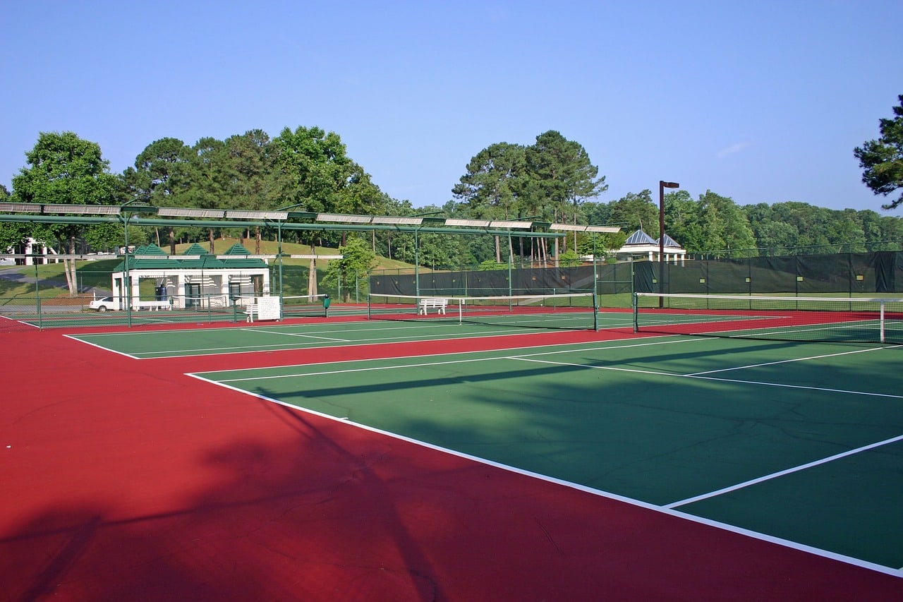 Outdoor tennis courts with long shadows across the playing surface