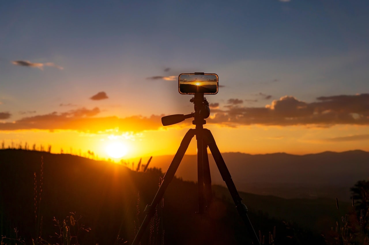 A person using a smartphone to photograph the sun near the horizon, illustrating future sun-path planning